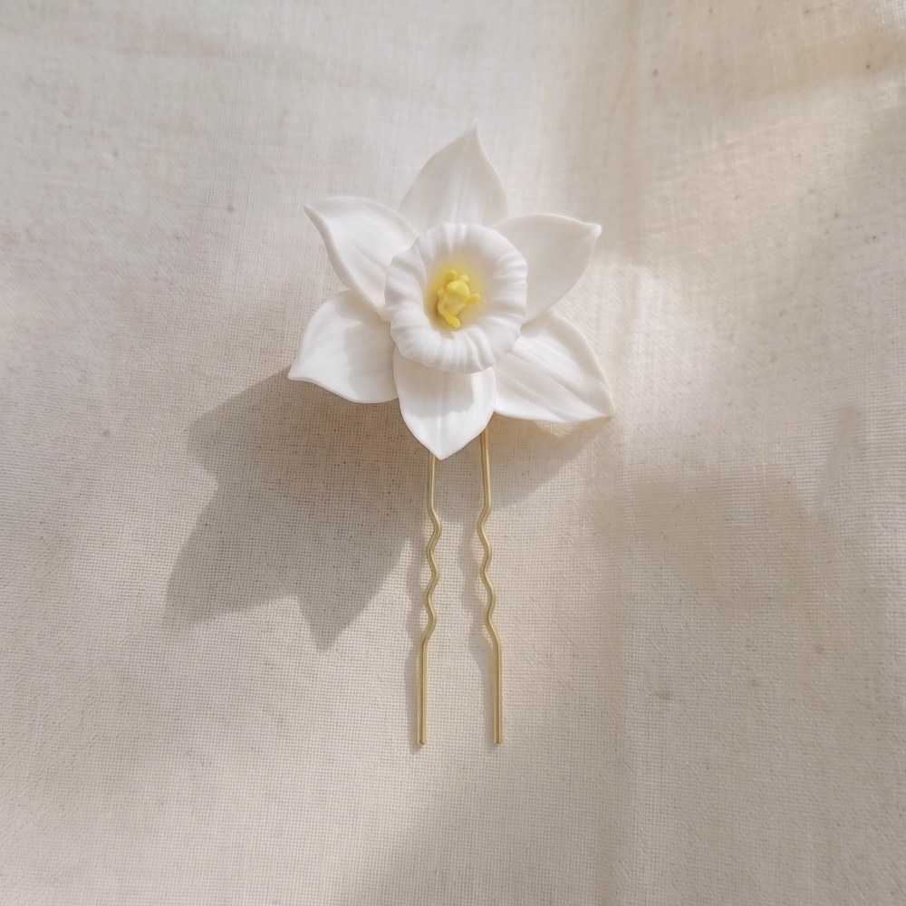 Ivory White cold porcelain daffodil with a yellow stamen centre on a gold U-shape hair pin